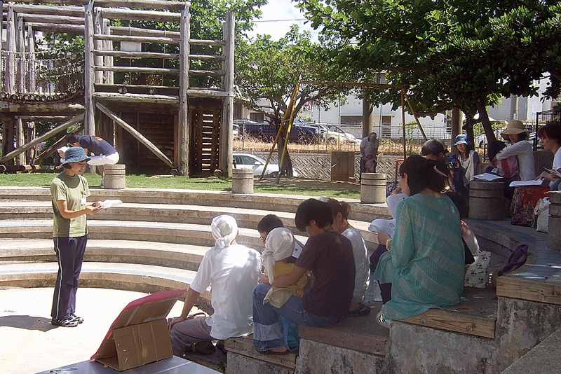 2011年の開園当初、那覇市の小禄すみれ児童公園で開かれた「青空・子育て支援・大地の会」。幼児教育について講話する金城さん（左）＝本人提供