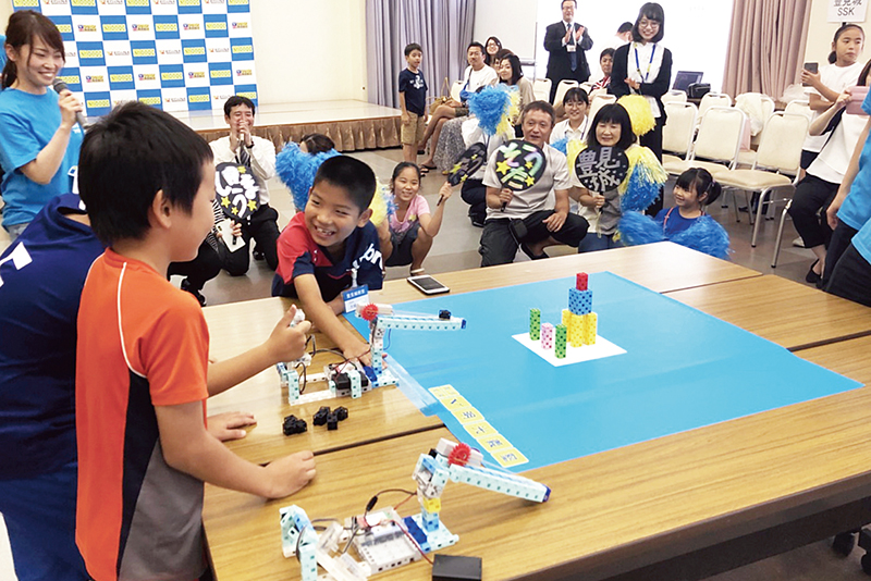 ロボットプログラミングを競う小学生。写真は明光義塾提供