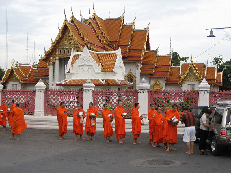 托鉢のため、はだしで列をなす僧侶たち。住民もはだしで地面に立って寄進を行う