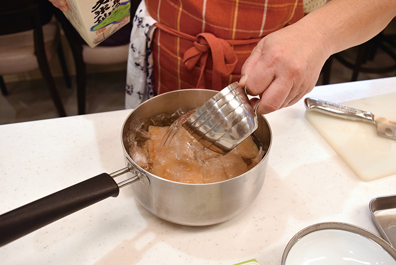 ３　厚手の鍋に分量のだしと豚三枚肉、泡盛を入れて＝写真、しばらく煮たら砂糖を加える。