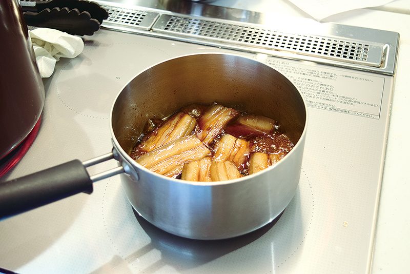 １　豚三枚肉はゆでて５～６センチ幅の５ミリ厚さに切り、泡盛、砂糖、しょうゆを煮立てた中に入れ、つやが出るまで煮る＝写真。