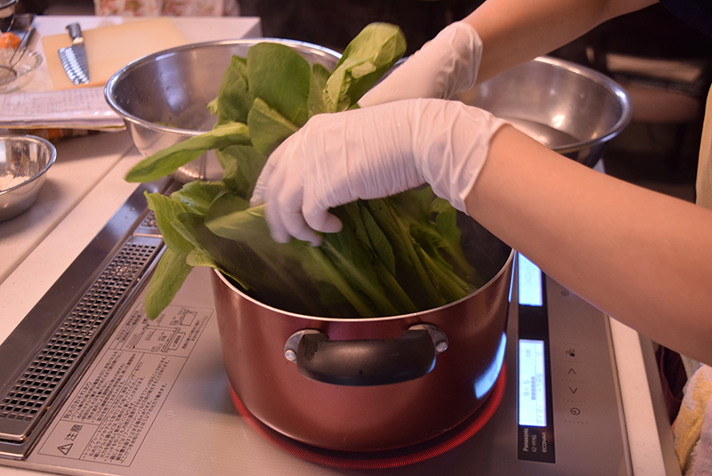 １　小松菜は根を切り落とし、株に十文字（太い場合は数を増やす）に切り込みを入れ、しばらく水に浸しておく。よく水洗いし、たっぷりの熱湯に塩を入れて、根元から先にゆで葉の部分も入れる＝上写真