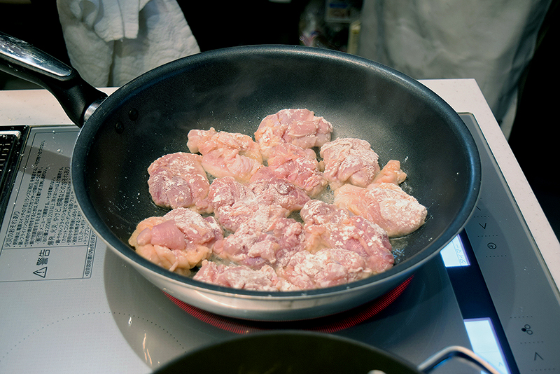１の鶏肉に小麦粉をはたきつけ、サラダ油をフライパンに熱して強火で焼き＝写真、皿に取り出す。フライパンに残った余分な油はペーパーで拭き取る。
