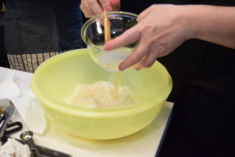 ３　１のご飯が炊きあがったら、コンブを取り出し、すしおけに移して２の合わせ酢を入れ＝写真、ふたをして５分間蒸らす。ふたを開け、しゃもじで切るように混ぜ合わせる。
