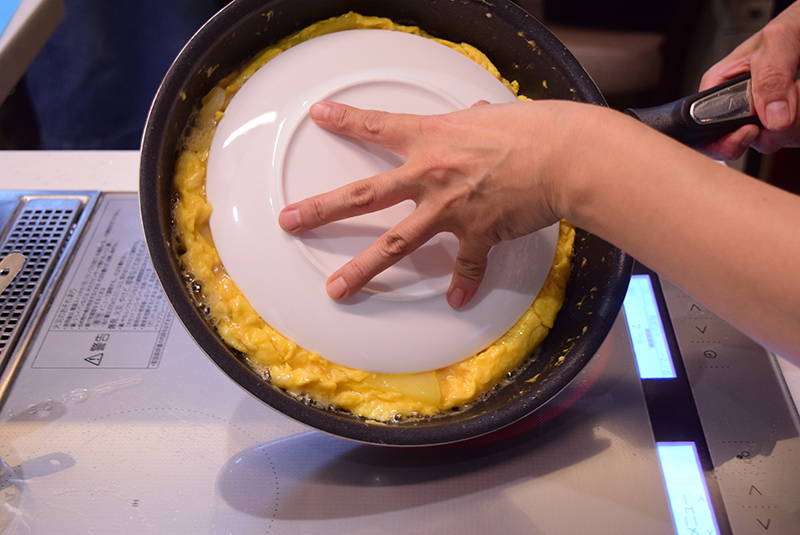焼き色が付いたら、鍋よりも一回り小さい皿（またはふた）を卵にかぶせて返し＝（４）、裏面も色よく焼き上げる。