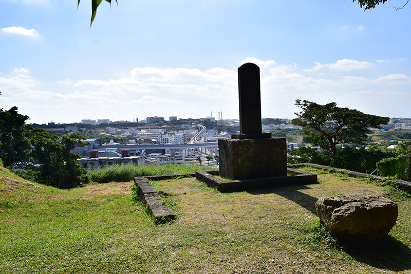 浦添城の前の碑。高台にあり、遠くに首里の街並みが見える。右下はノロ（神女）が馬に乗るための踏み台にした「馬ヌイ石」